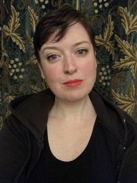 a white woman in her 40s with short dark hair. She's wearing red lipstick and smiling slightly. This is me.