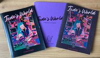 Three books on a wooden desk. Two are Jude's World zines with a colourful cover depicting a young person with turquoise hair writing in their diary. One is shiny, the other is matte. In the middle and slightly obscured by the zines is a purple workbook with Jude's World companion workbook on the cover